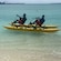 2 men riding a 2 seat water bike at a beach